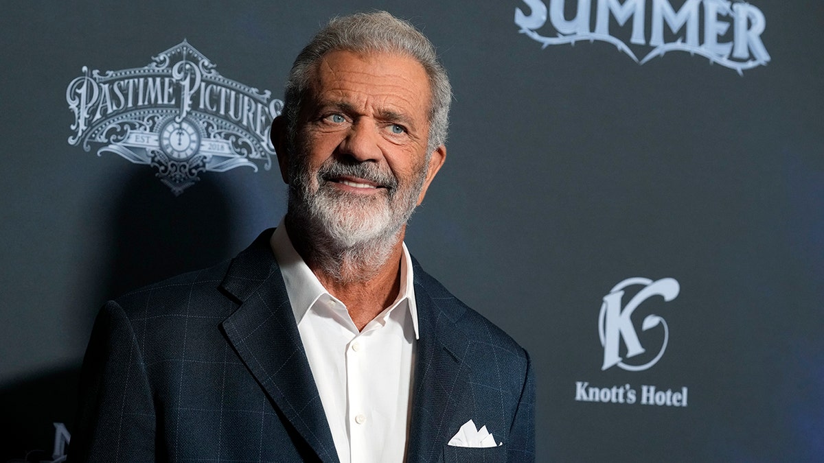 Mel Gibson in a blue suit smiles on the carpet