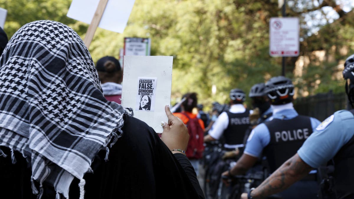 Un manifestante antiisraelí en la Convención Nacional Demócrata sostiene un cartel con una pequeña foto de la vicepresidenta Kamala Harris junto a las palabras "Genocidio es fascismo".