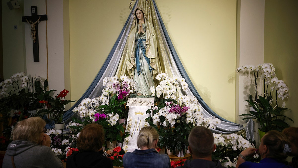 Una estatua de la Virgen María rodeada de flores. 