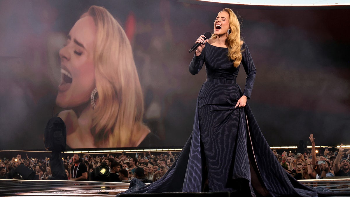 Adele sings on stage with a video in the background