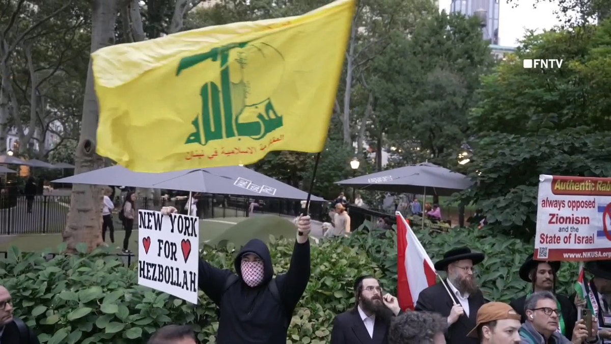 Manifestante anti-Israel sosteniendo un cartel y una bandera de Hezbolá