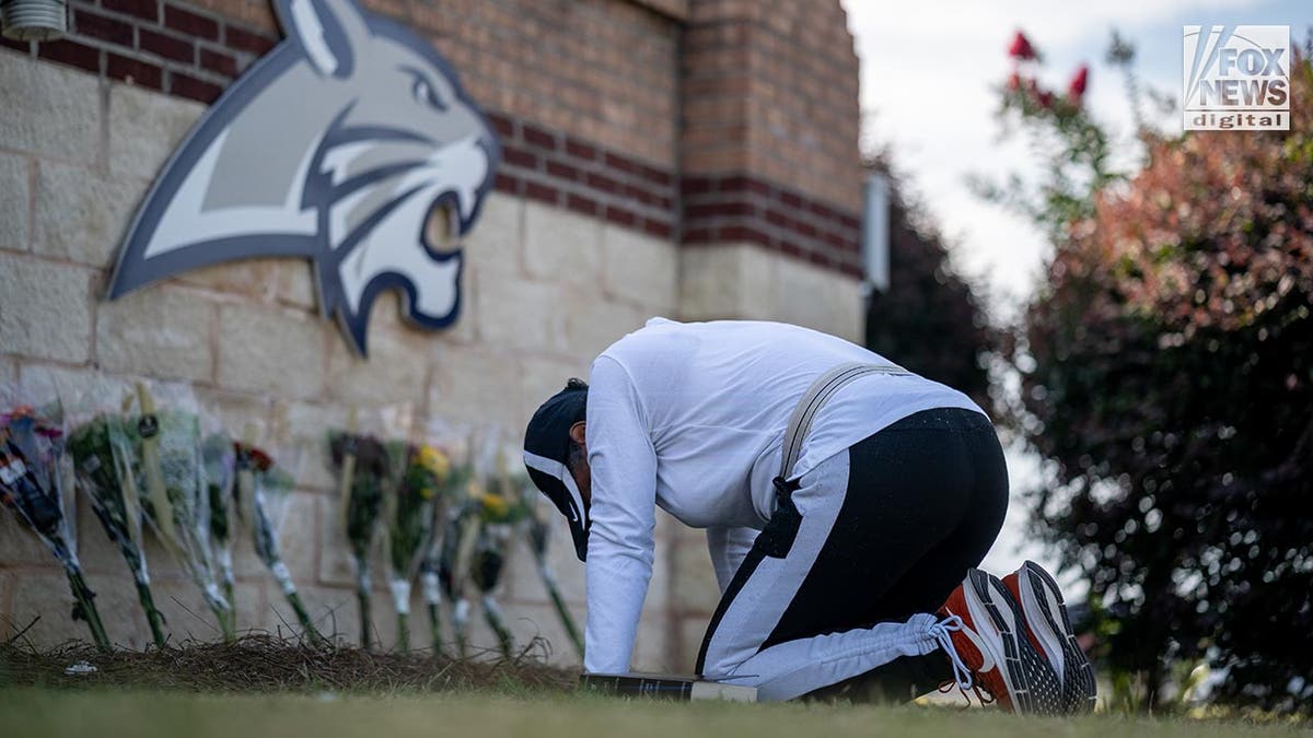 Una mujer se arrodilla junto a un monumento en memoria de los muertos en el tiroteo de la escuela Apalachee de Gerorgia