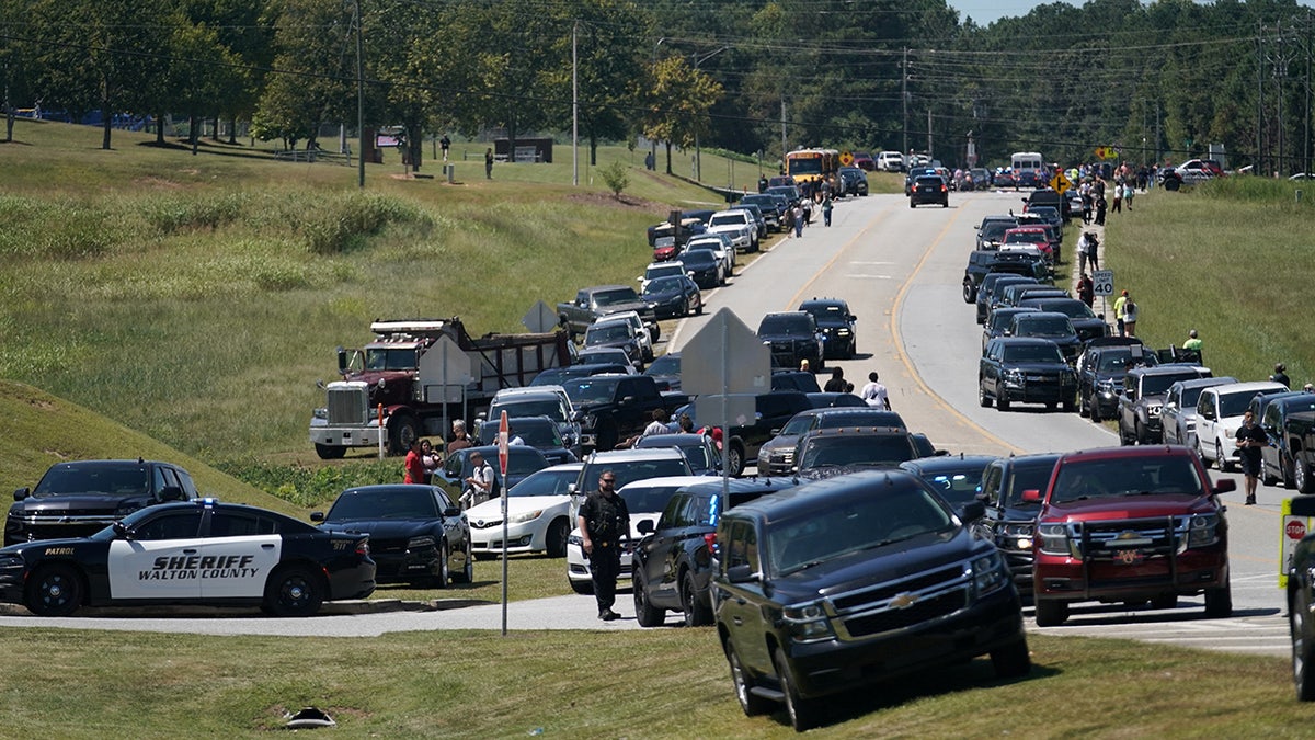 Cars are parked along the road while law enforcement officers work on the scene following the shooting at Apalachee High School