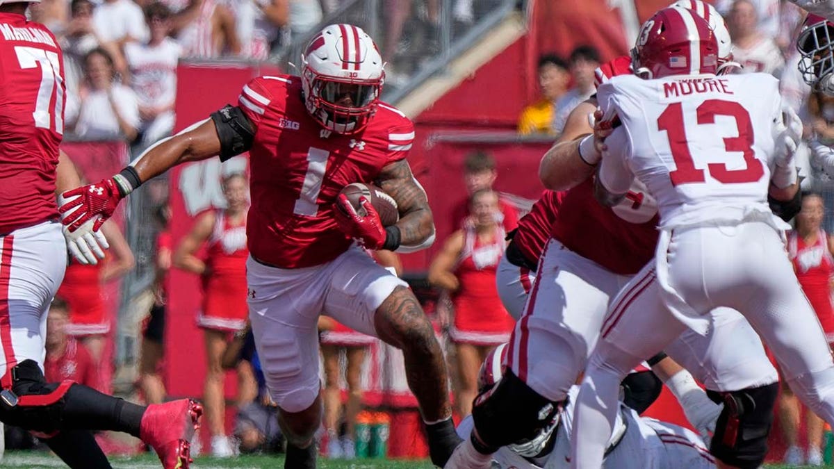 Jogador de Wisconsin corre com a bola de futebol