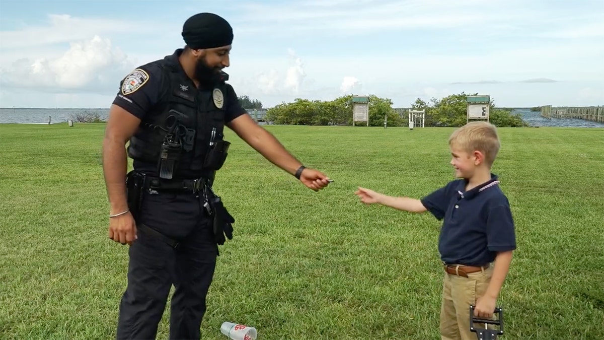 An serviceman  hands a kid  a reward coin