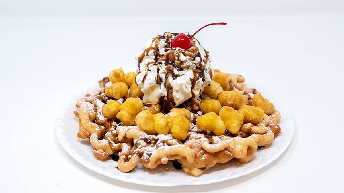 Funnel cake with ice cream on top and a cherry.