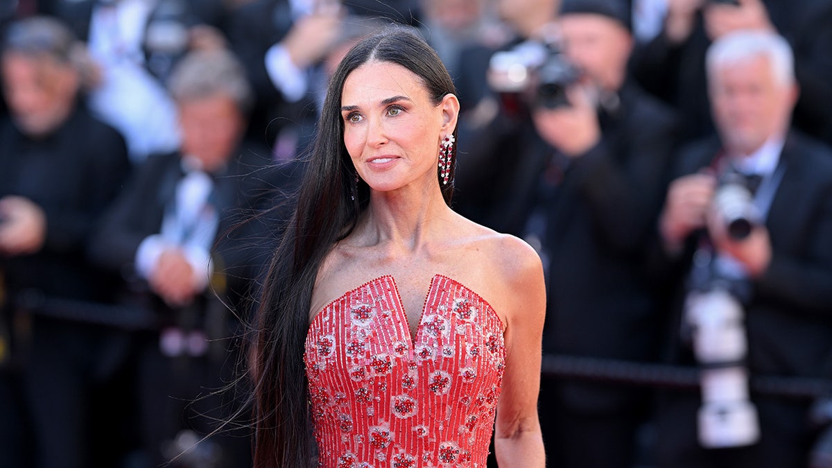 Demi Moore posando en la alfombra roja con un vestido rojo