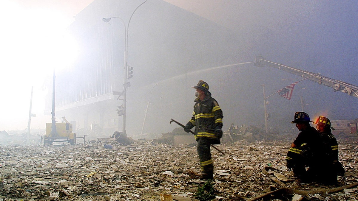 A firefighter walks through the rubble of the Twin Towers of the World Trade Center in New York on September 11, 2001, holding an American flag hanging from a traffic light post. Two planes controlled by the hijackers collided with the buildings, destroying both buildings.