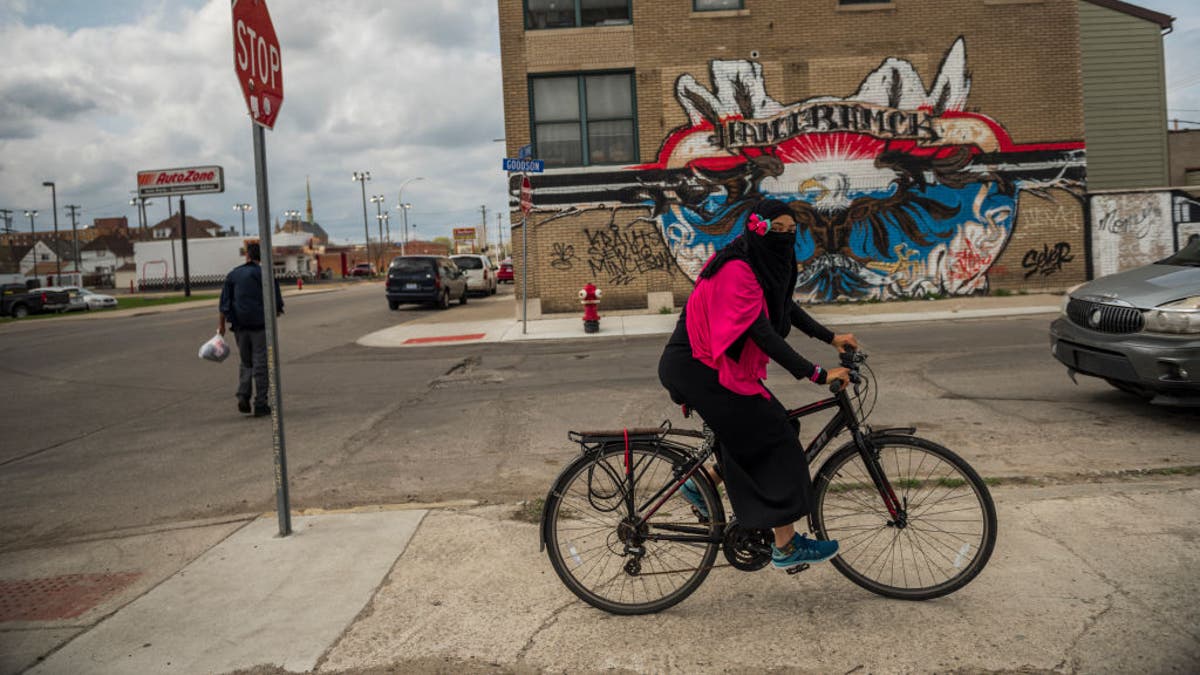 Mujer musulmana cubierta, montando en bici en Hamtramck, Mich. en una foto de 2017