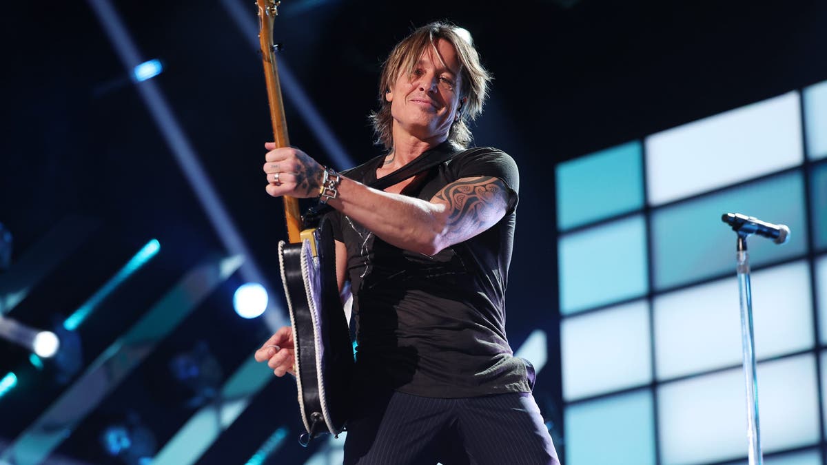 keith urban sujetando una guitarra en el escenario