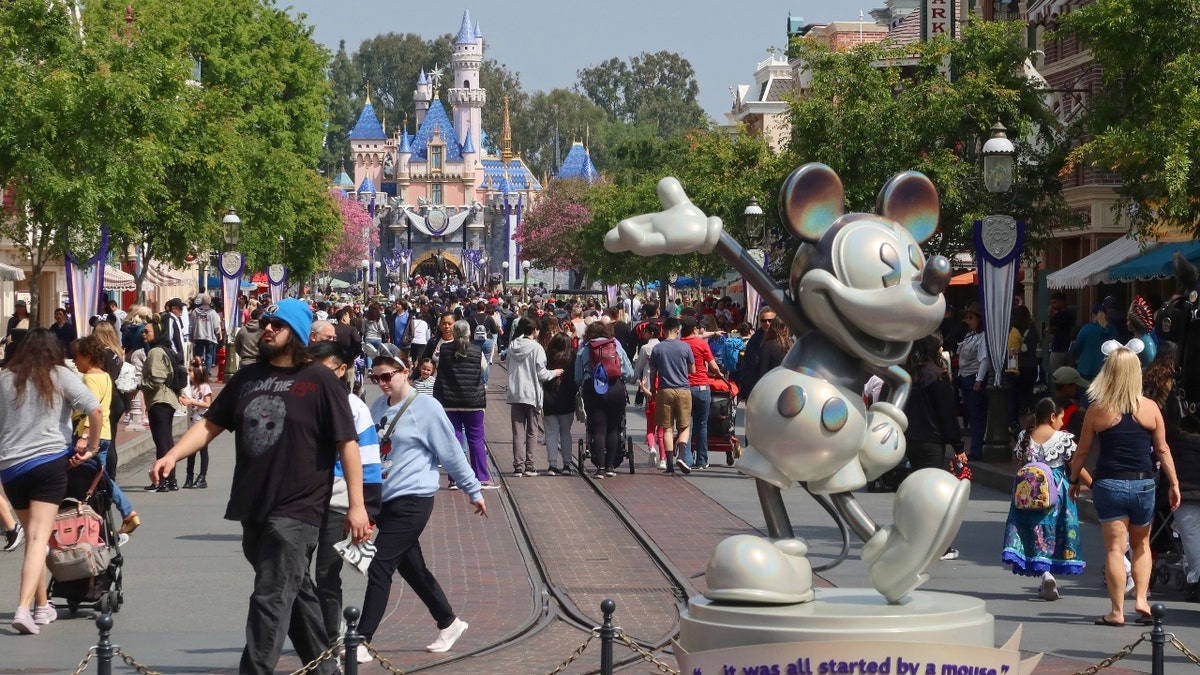 La gente camina junto a Mickey Mouse por Main Street en Disneylandia