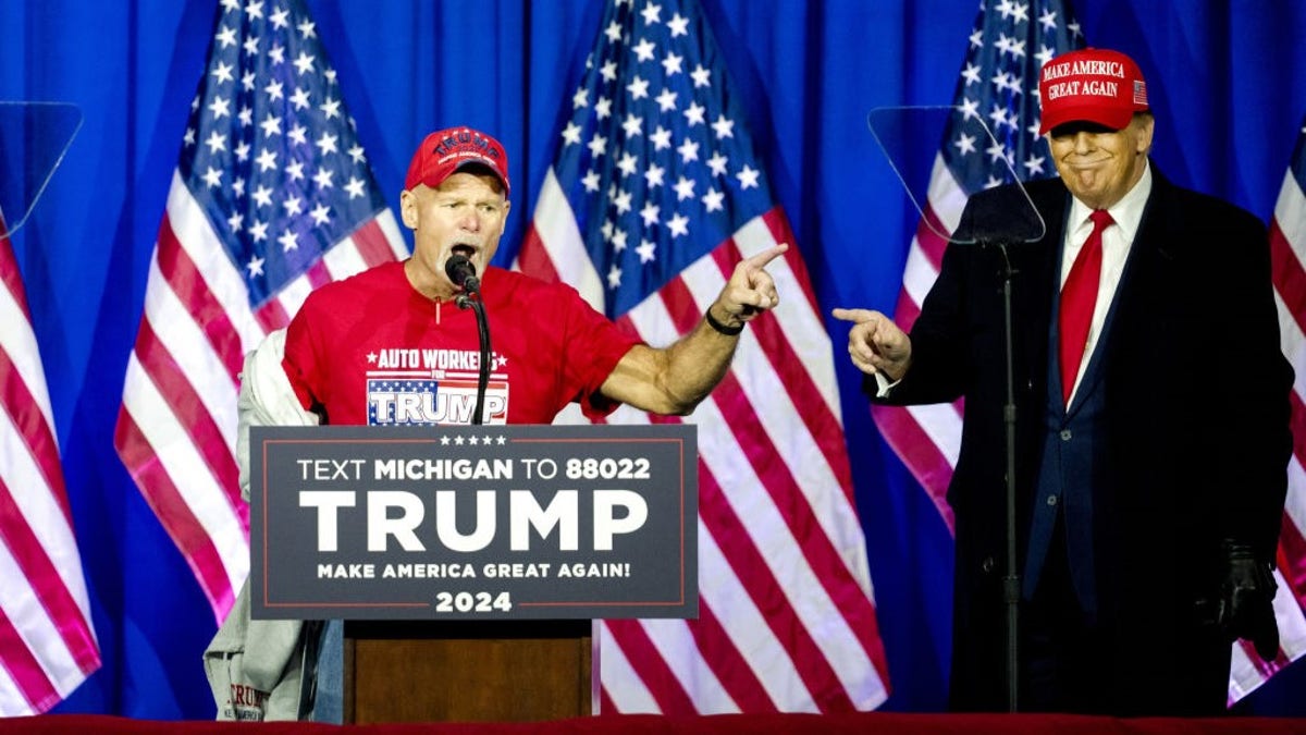 Brian Pannebecker di podium dengan mantan Presiden Trump di sebelah kirinya