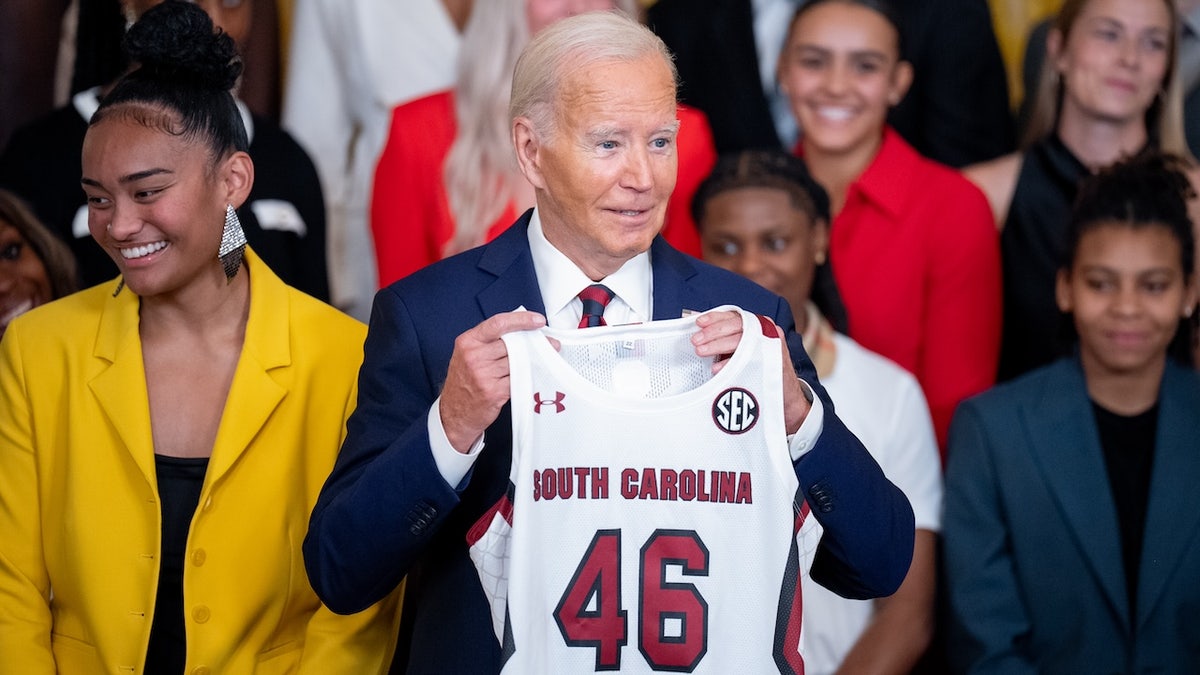 U.S. President Joe Biden holds up a team jersey