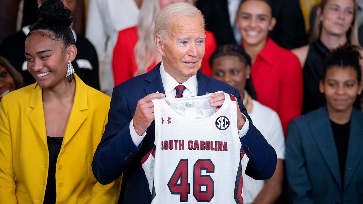 U.S. President Joe Biden holds up a team jersey