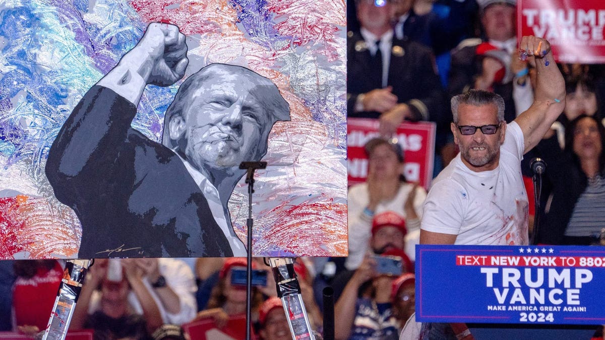 Scott LoBaido mimics the pose of former President Trump with a raised fist after finishing a speed painting of the GOP candidate