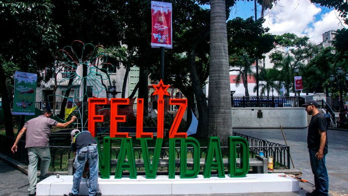 Men work on the installation of a christmas sign in Caracas on November 2, 2017.