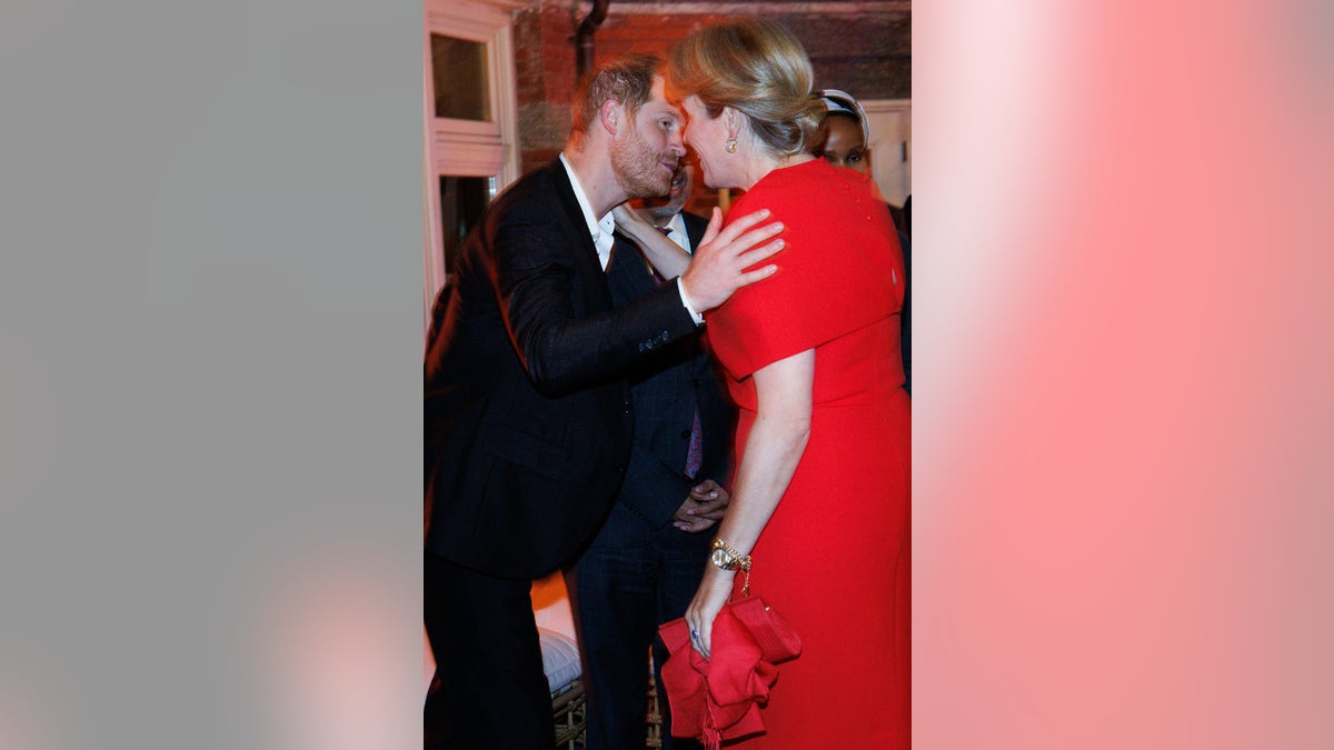 Prince Harry leaning in to kiss the queen of Belgium on the cheek.