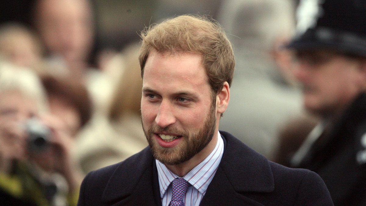 An older photo of Prince William in a suit with a beard.