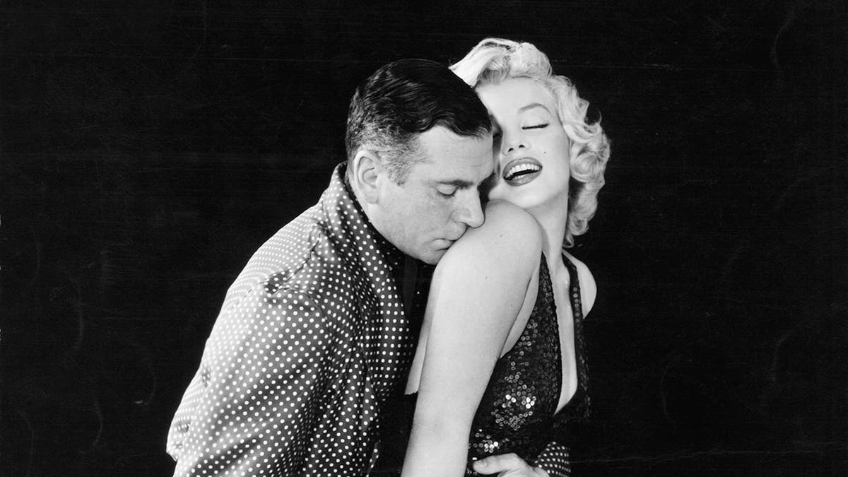 Marilyn Monroe siendo besada en el hombro por Laurence Olivier.