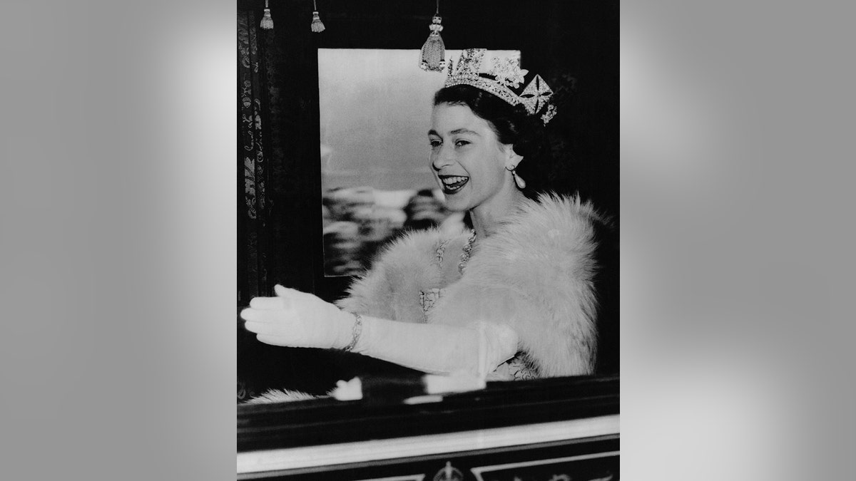 Queen Elizabeth smiling inside a royal carriage.