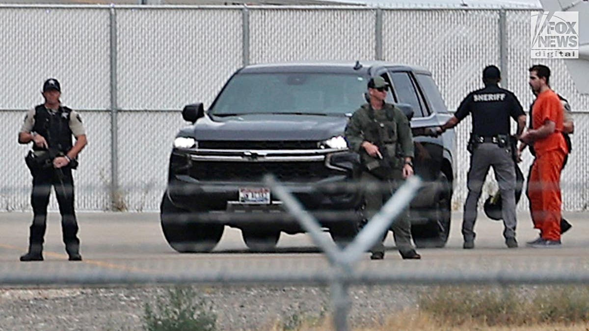 Bryan Kohberger, wearing an orange prison jumpsuit, was led by a black SUV on an airport tarmac