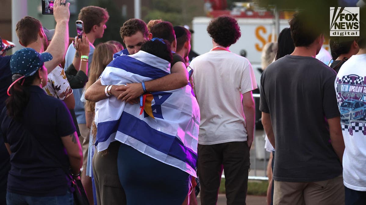 Estudantes se abraçam envoltos em bandeiras americanas e israelenses