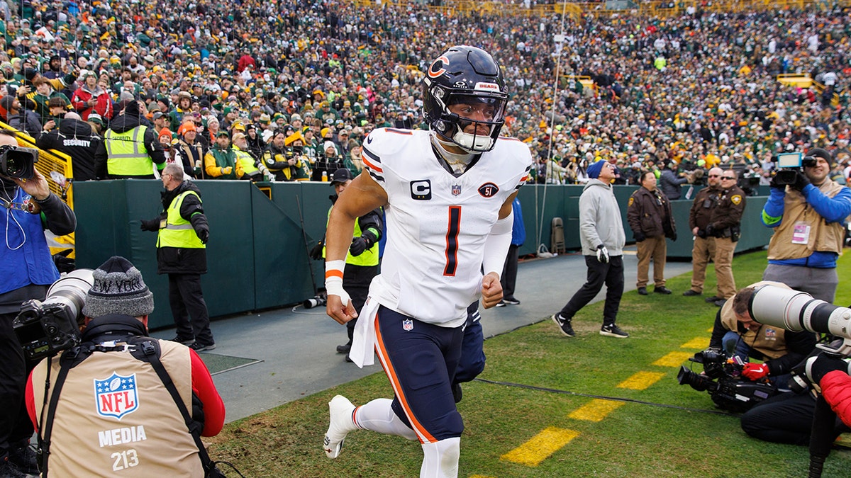 Justin Fields entra trotando en el campo de fútbol americano