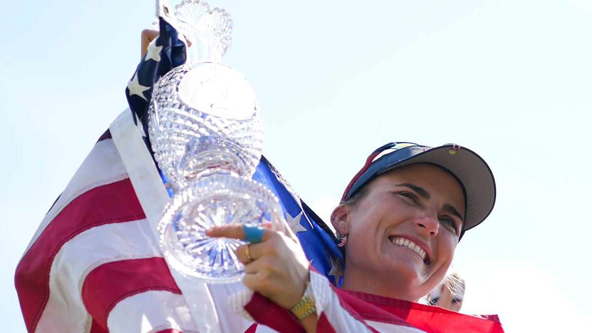 Lexi Thompson sonríe con la bandera estadounidense sobre los hombros