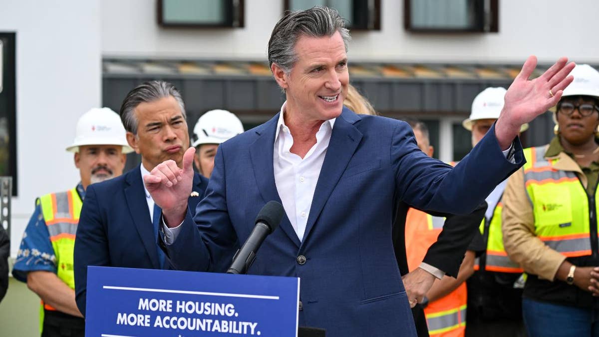 Gavin Newsom at lectern with sign readng 