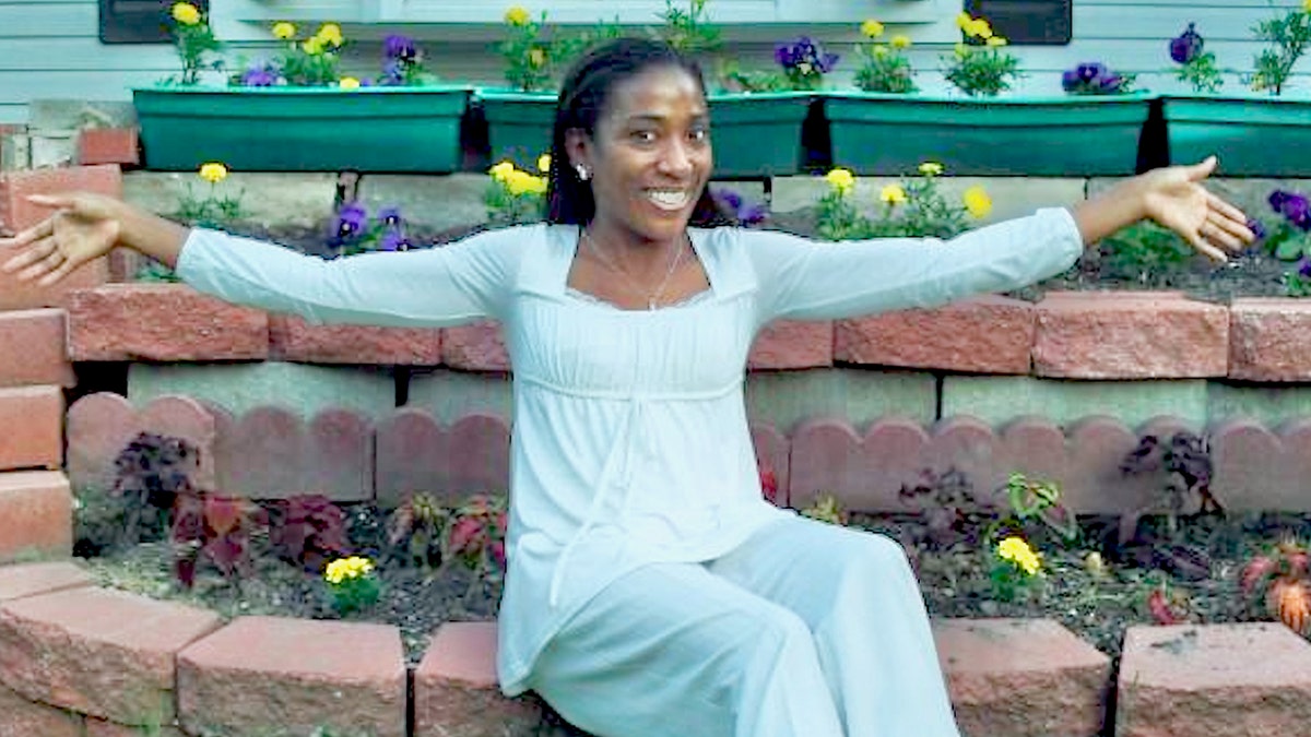 Genai Coleman sits in a garden with his arms outstretched in white