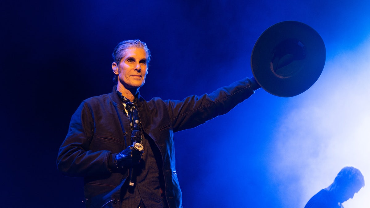 Perry Farrell de pie en el escenario con el sombrero en la mano