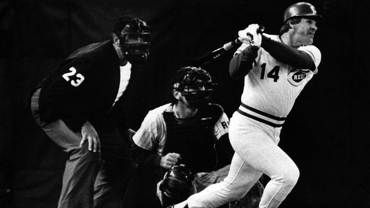 El árbitro Lee Weyer y el receptor de San Diego Bruce Bochy tienen los mejores asientos de la casa mientras Pete Rose golpea el hit No. 4,192 para romper el récord de Ty Cobb.