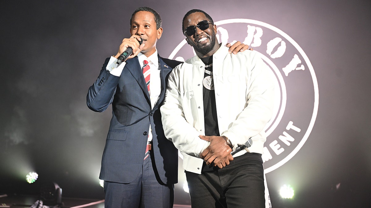 Shyne envolve seu braço em volta de Sean Diddy Combs em um show.