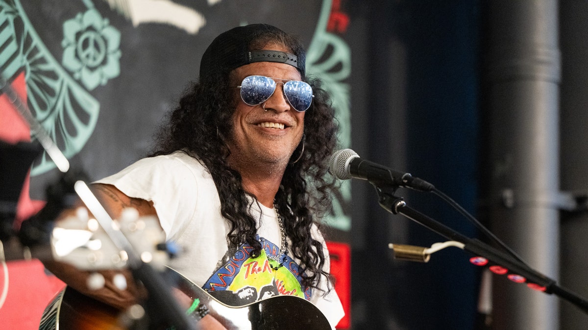 Slash sits in front of a microphone