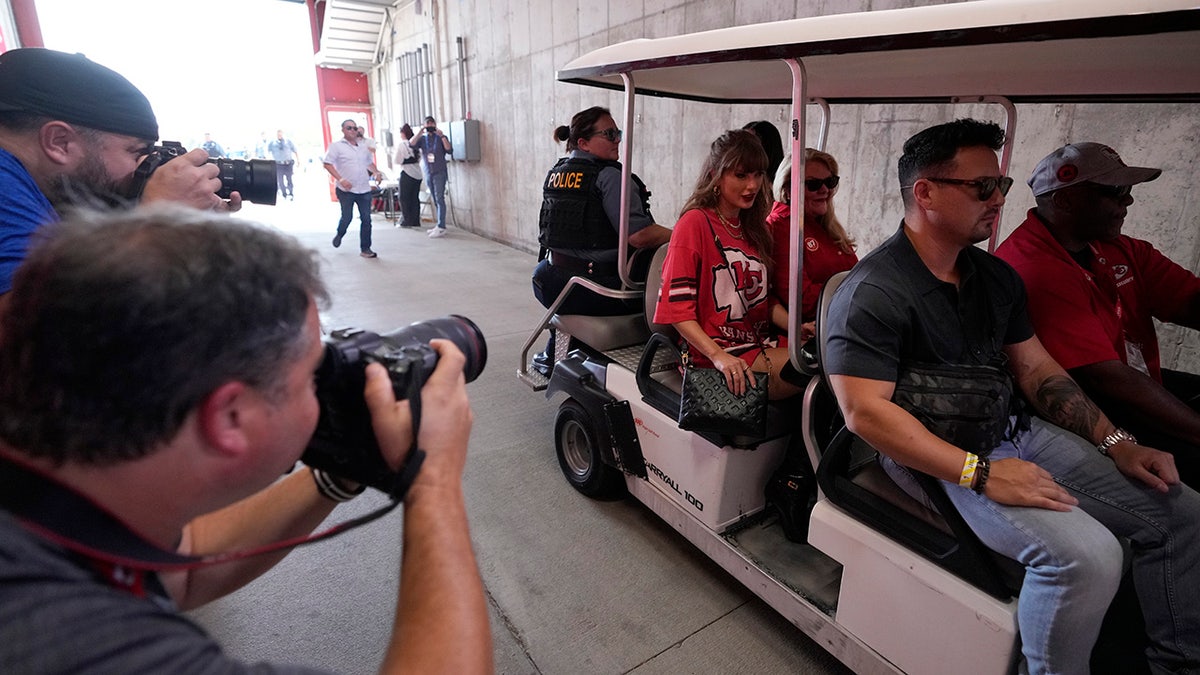 Taylor Swift rides in a cart