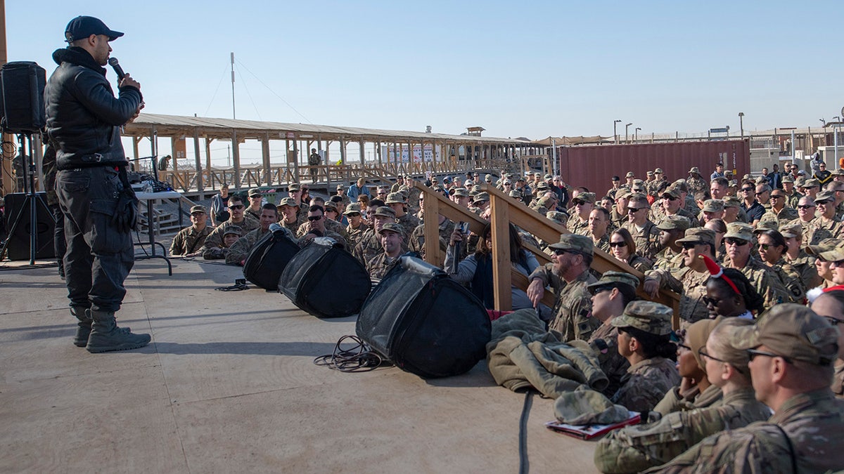 Wilmer Valderrama speaking to an audience of soldiers.