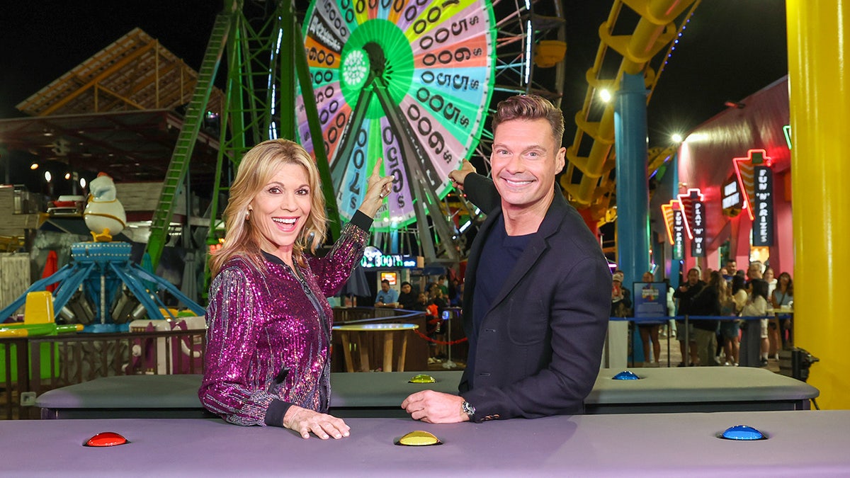 Vanna White and Ryan Seacrest point at the Santa Monica ferris wheel lit up like 