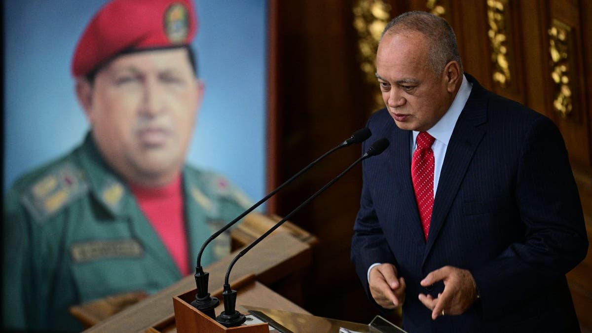 Venezuela's Interior Minister Diosdado Cabello speaks next to a painting of the late Venezuelan President Hugo Chavez 