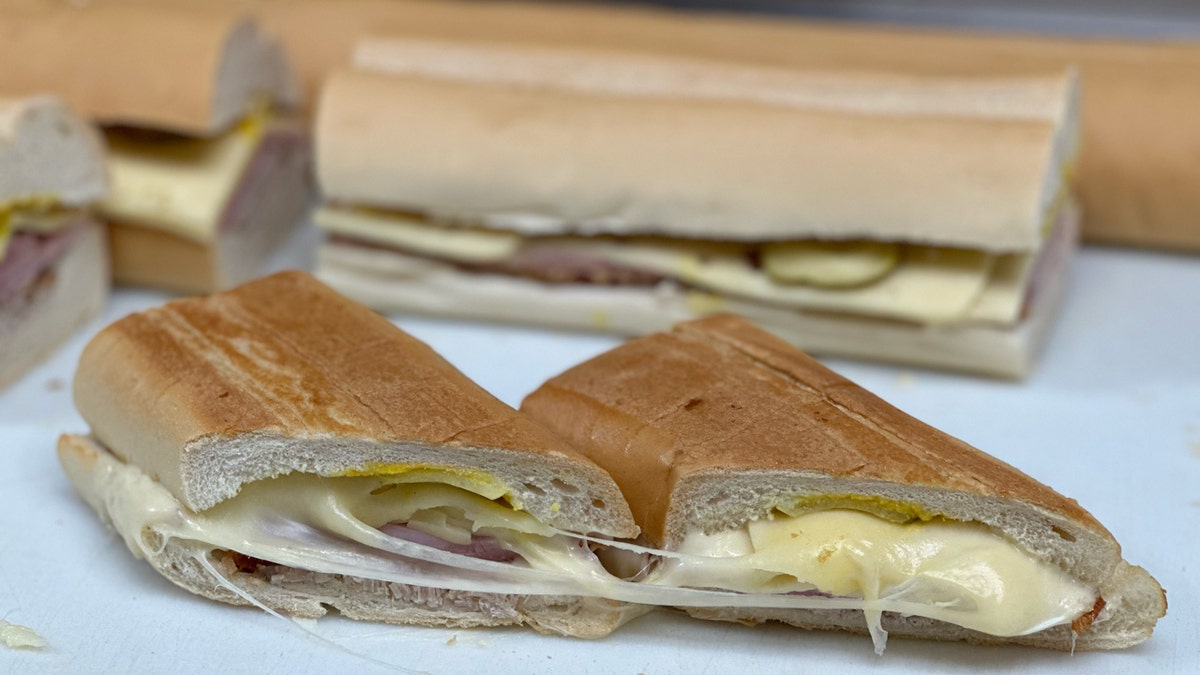 Un sándwich cubano recién prensado de Versalles se ve sobre una tabla de cortar en la cocina del restaurante de Miami, 26 de septiembre de 2024.