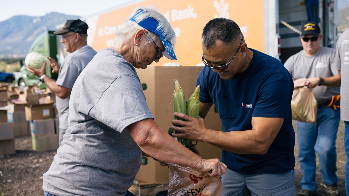 Volunteers packing corn into a bag at a volunteer event.