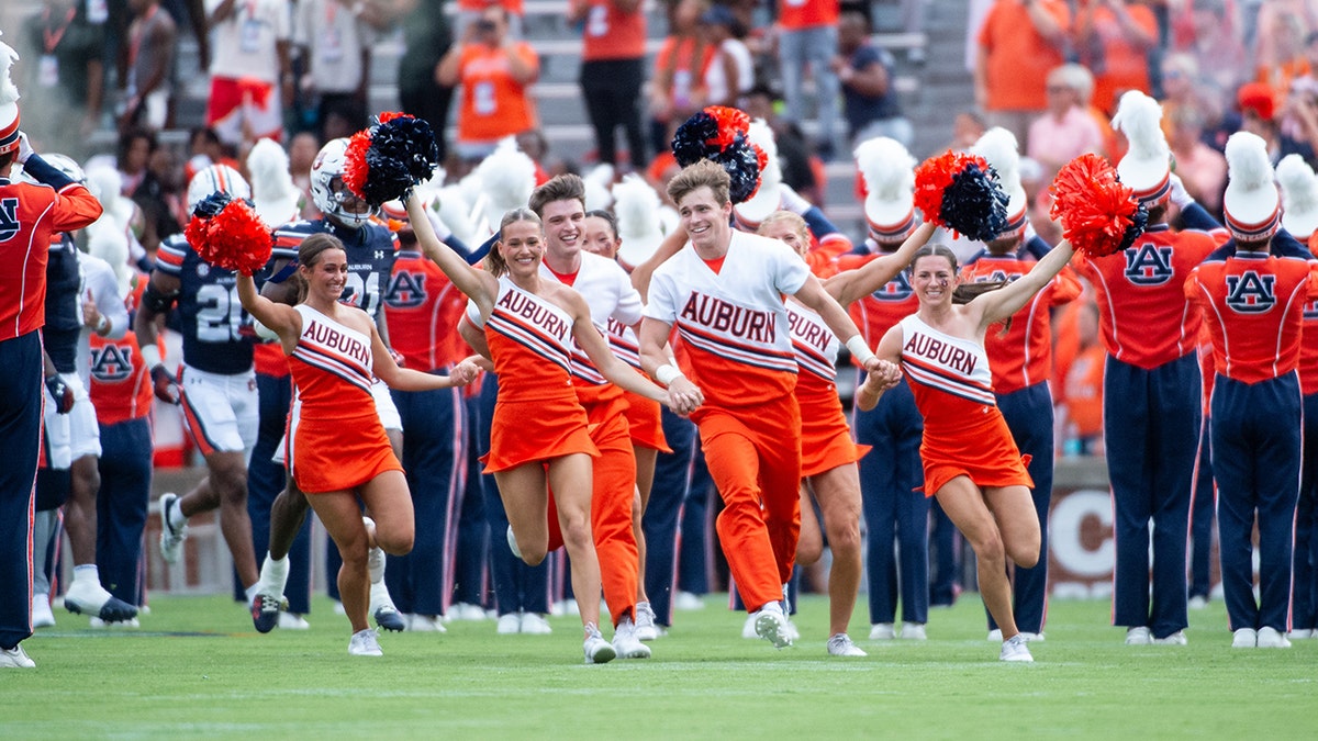 Auburn cheerleader knocks down Oklahoma player running onto field while performing stunts  at george magazine