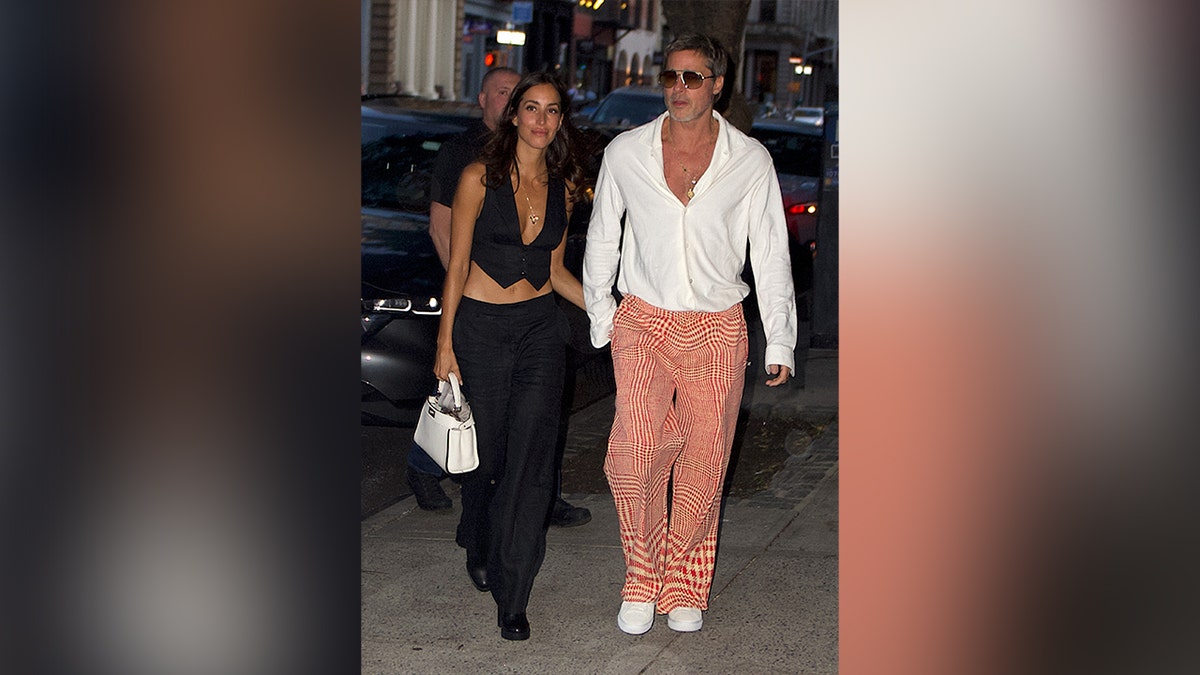 Ines de Ramon in an all black outfit and Brad Pitt in checkered red pants and a white shirt.