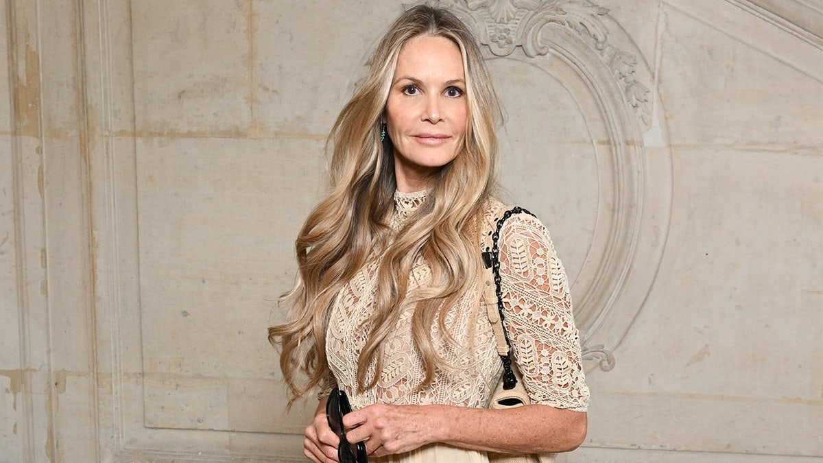 Elle Macpherson con un top blanco de encaje mira directamente a la cámara