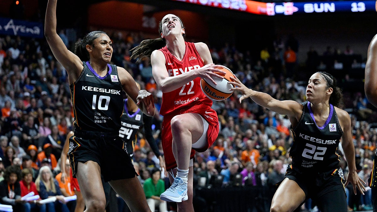 La escolta de las Indiana Fever Caitlin Clark, nº 22, se dirige a la canasta mientras la alero de las Connecticut Sun Olivia Nelson-Ododa, nº 10, y la escolta Veronica Burton, nº 22, defienden durante la primera mitad del segundo partido de la primera ronda de la serie de playoffs de baloncesto WNBA el miércoles 25 de septiembre de 2024, en Uncasville, Connecticut.