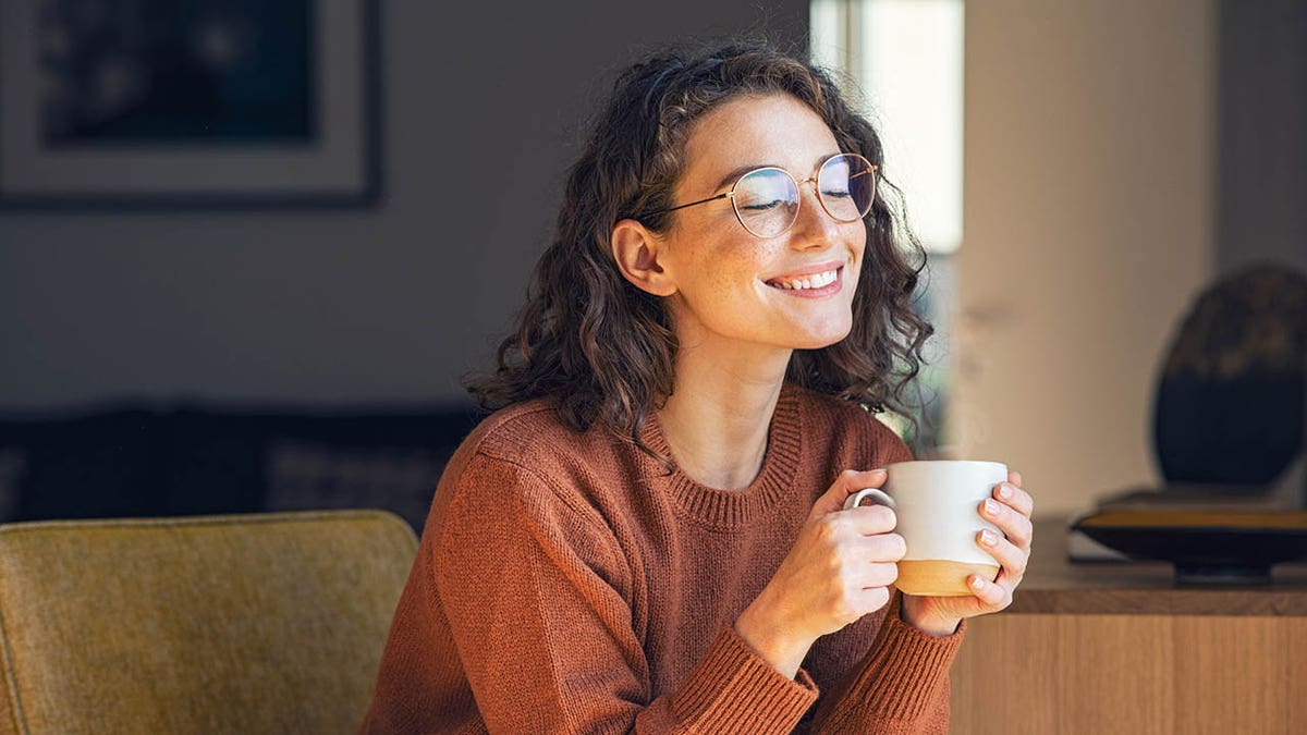 Mujer sonriendo con bebida caliente