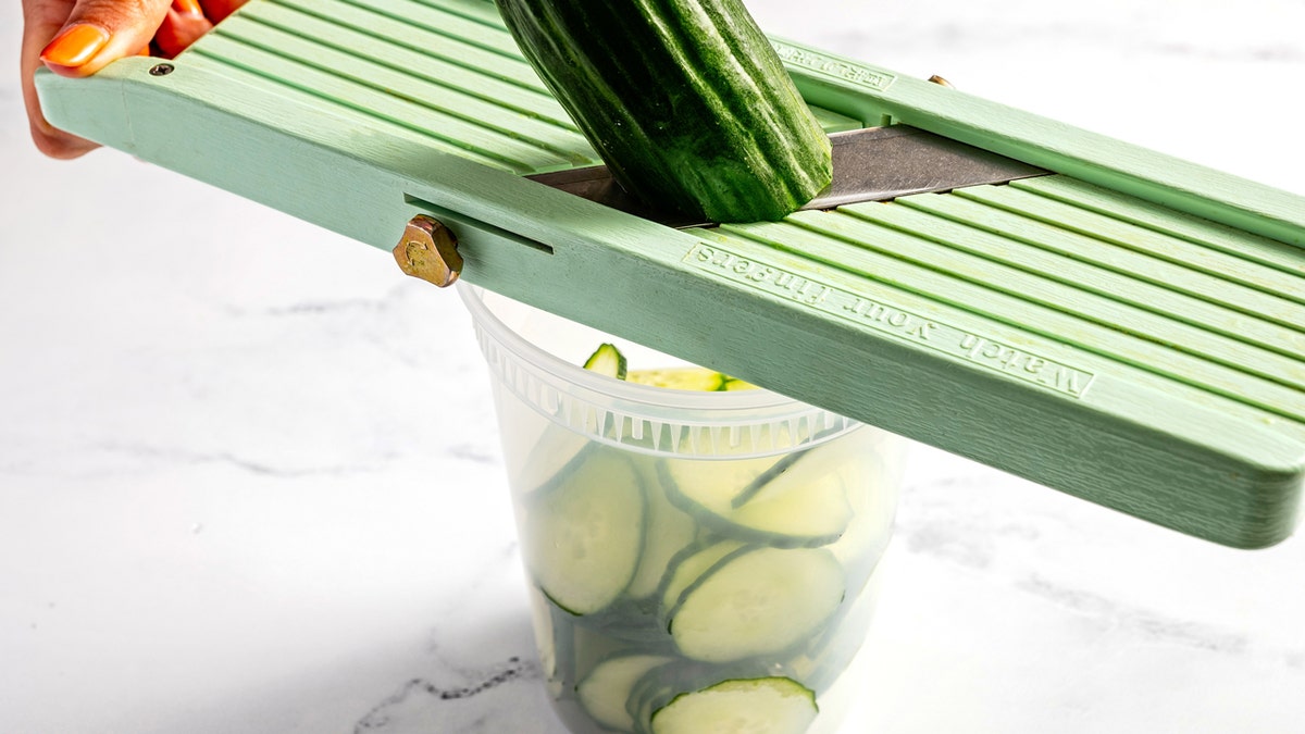 A person slicing cucumber