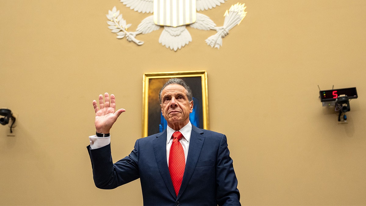 Former New York Governor Andrew Cuomo raises his hand to take the oath before testifying