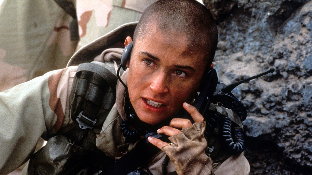 Demi Moore segura um telefone com equipamento militar em uma foto de GI Jane