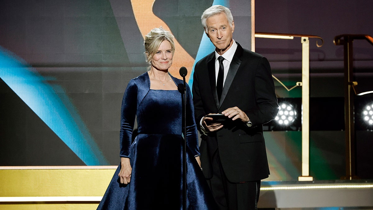 Mary Beth Evans in a blue velvet dress and Drake Goestyn in a black suit and tie appear on stage at the Daytime Emmy Awards in 2023