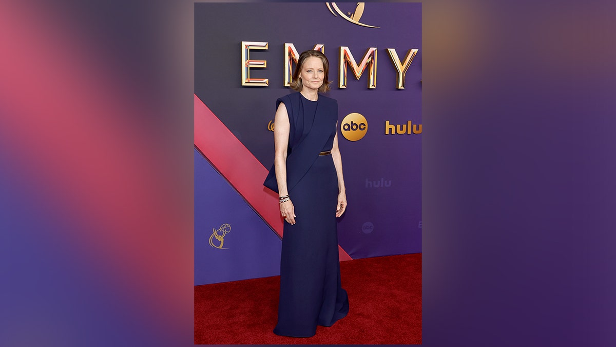 Jodie Foster, dinominasikan atas karyanya di "Detektif Sejati: Negara Malam," mengenakan gaun biru di karpet merah Emmy Awards 2024.